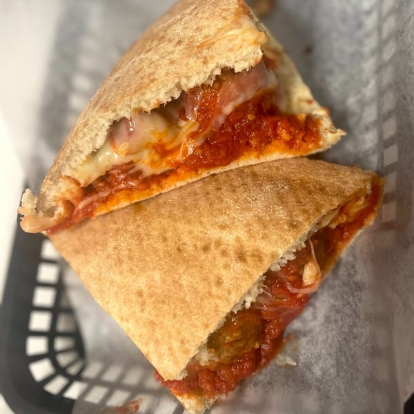 A Johnny's Pockets calzone, cut in half, revealing melted cheese, pepperoni, and rich tomato sauce.