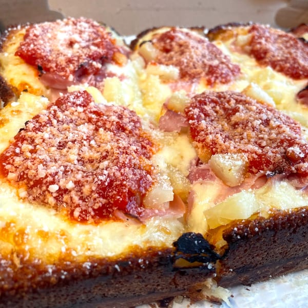 Close-up of a Detroit-style pizza from Johnny's Pockets with pineapple, ham, and tomato sauce.