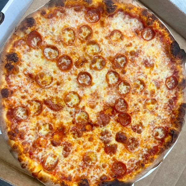 A whole pepperoni pizza from Johnny's Pockets, with melted cheese and a crispy crust, in a box.