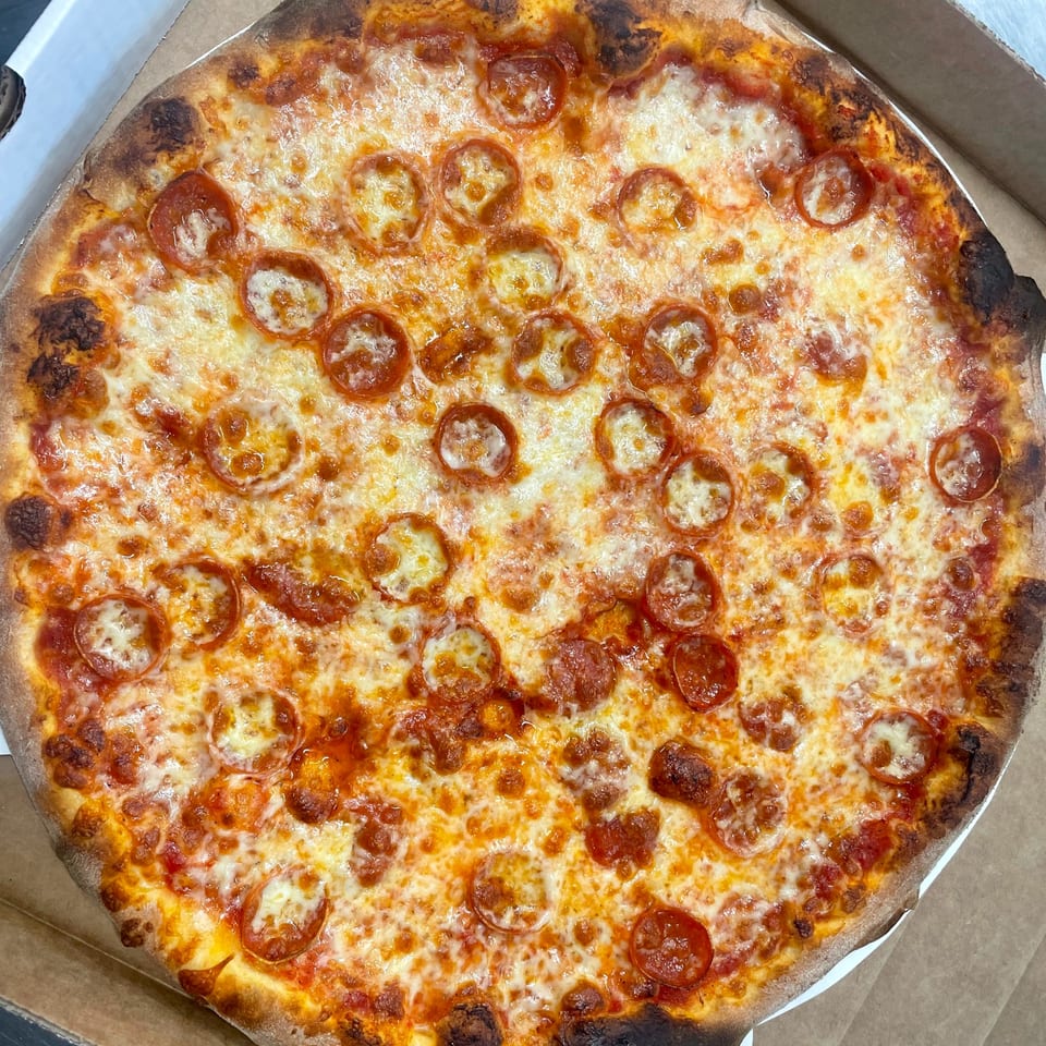 A whole pepperoni pizza from Johnny's Pockets, with melted cheese and a crispy crust, in a box.