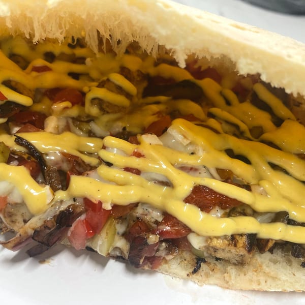 Close-up of a Johnny's Pockets pizza pocket, filled with meat, vegetables, and drizzled with cheese sauce.